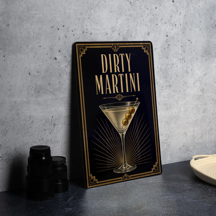 A framed poster of a Dirty Martini cocktail is displayed on a wall, accompanied by a stack of black camera lenses and a white dish.