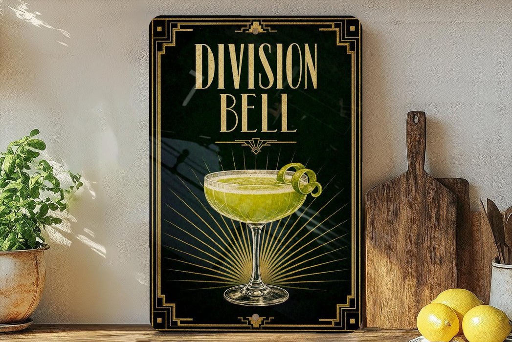 a framed advertisement for a cocktail called "Division Bell", which is displayed on a wall next to a wooden cutting board and some lemons.