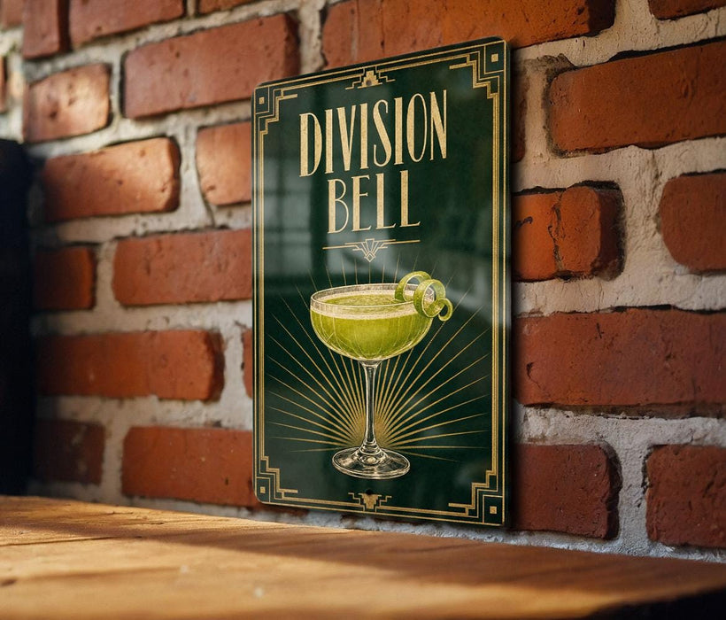A sign with the text "DIVISION BELL" and an illustration of a cocktail glass with a lemon twist, mounted on a brick wall.