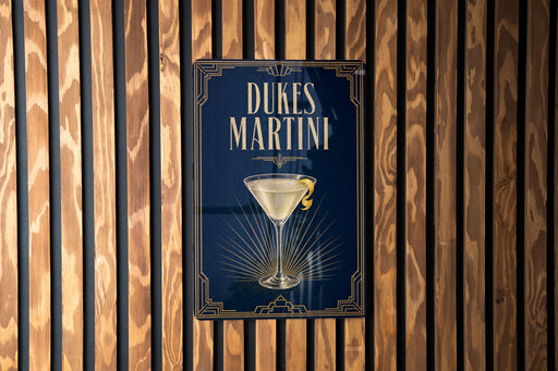 A sign for Dukes Martini is displayed on a wooden wall.