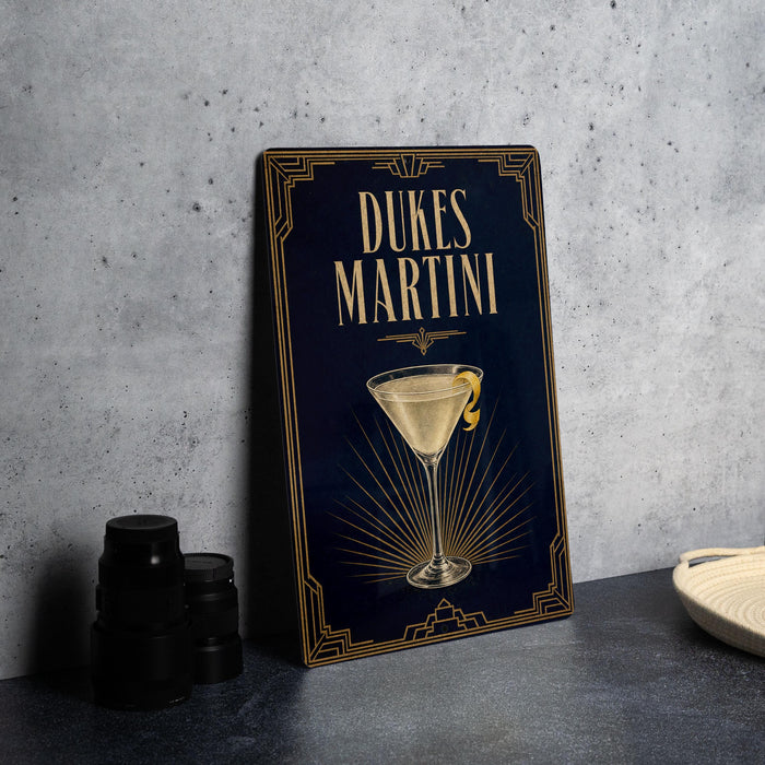 A framed image of a Dukes Martini cocktail on a dark blue background, with a golden border and a stylized illustration of the drink.