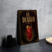 a decorative sign for "El Diablo", which is a cocktail, placed on a table next to some black camera lenses.