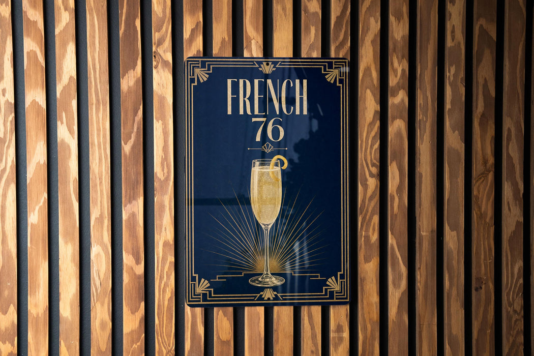 A poster with the text "FRENCH 76" and an illustration of a champagne glass is displayed on a wooden wall.