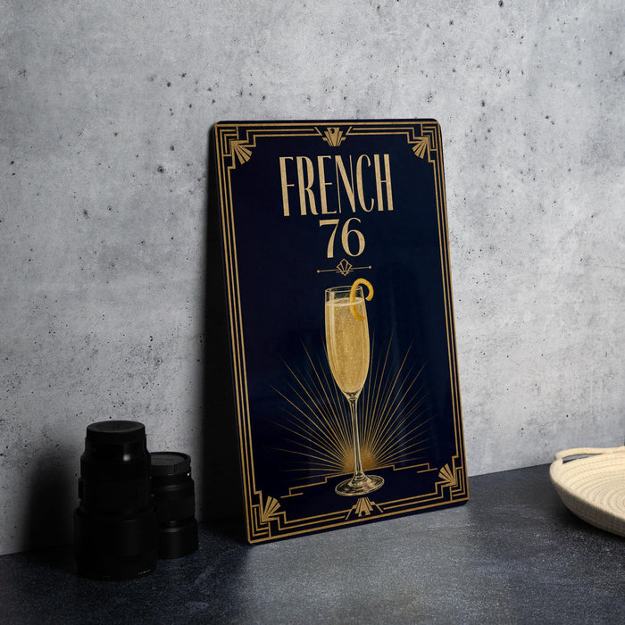 A framed poster with the text "FRENCH 76" and an illustration of a champagne glass is displayed on a table.