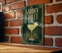A sign with the text "GARDEN GIMLET" and an illustration of a cocktail glass with a lime slice, mounted on a brick wall.