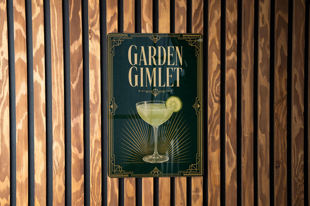 A sign for a cocktail called "Garden Gimlet" is displayed on a wooden wall.