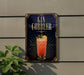 A sign for a gin cobler cocktail is displayed on a wall, with a plant visible to the left.