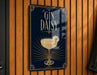 A sign with the text "GIN DAISY" and an illustration of a gin and tonic drink, with a single white flower on the rim of the glass.