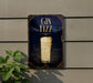 A sign for a gin fizz cocktail is displayed on a wall, with a plant visible to the left.