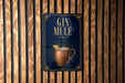 A sign for a gin mule, featuring a copper mug with a lemon slice, is displayed on a wooden wall.