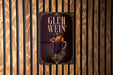 A poster with the text "GLUH WEIN" and an illustration of a hot beverage, likely a mulled wine or spiced hot chocolate, is displayed on a wooden wall.