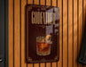 A sign with the word "GODFATHER" and an illustration of a cocktail is displayed on a wooden wall.