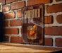A sign with the word "GODFATHER" and an illustration of a cocktail glass with an orange slice, mounted on a brick wall.