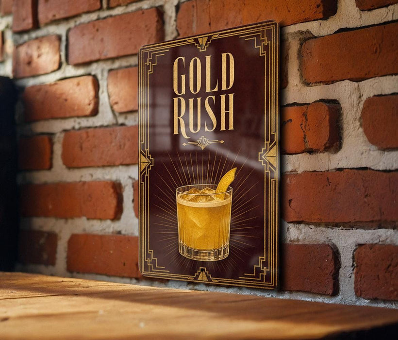 A sign with the text "GOLD RUSH" and an illustration of a cocktail is displayed on a brick wall.