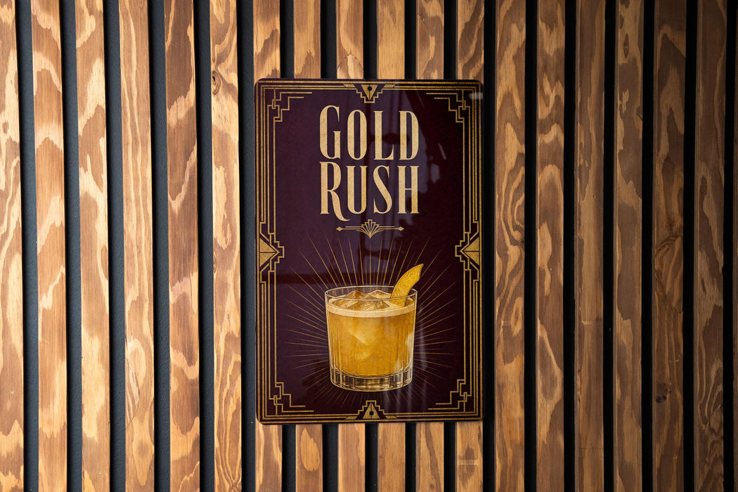 A poster with the text "GOLD RUSH" and an illustration of a cocktail is displayed on a wooden wall.