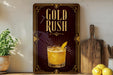 A framed advertisement for a cocktail called "Gold Rush" is displayed on a wall, featuring an illustration of a cocktail glass with a lemon slice.