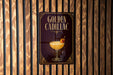 A sign for "Golden Cadillac" cocktail is displayed on a wooden wall.