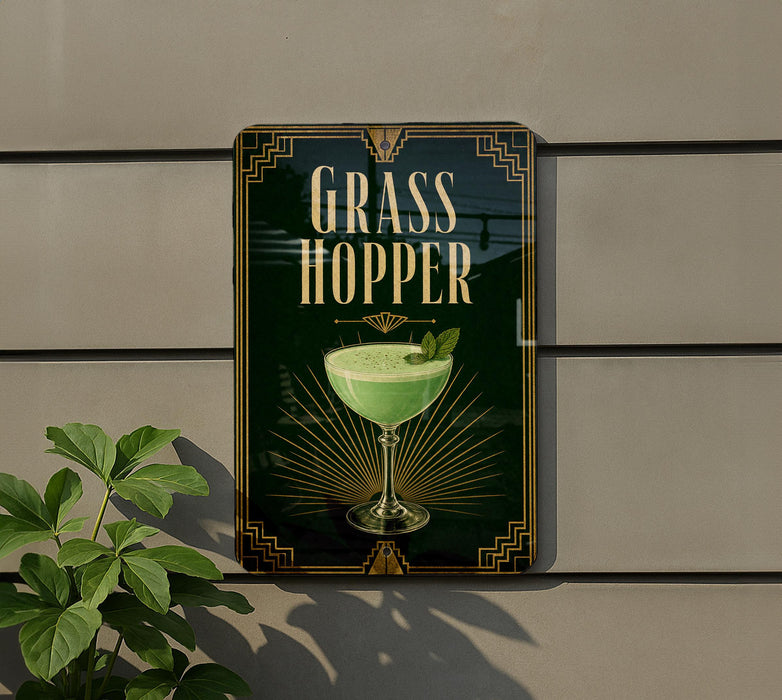 A sign for a "Grass Hopper" cocktail, featuring a green drink in a glass with a leaf garnish, is displayed on a wall.