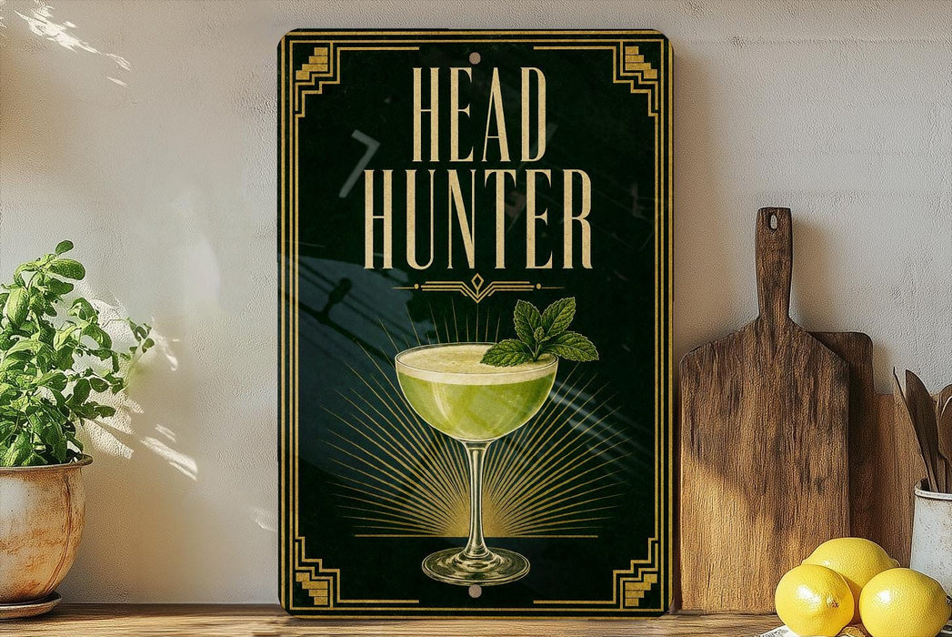 a decorative sign with the text "HEAD HUNTER" and an illustration of a cocktail glass with a mint leaf garnish. The sign is displayed on a shelf next to a wooden cutting board and a potted plant.