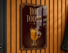 A sign that reads "HOT TODDY" with an illustration of a hot beverage, likely a hot chocolate or tea drink, on a wooden wall.