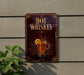 A sign on a wall advertising "Hot Whiskey" with a glass of whiskey and a lemon slice.