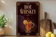 A decorative sign with the text "HOT WHISKEY" and an illustration of a hot whiskey drink with a lemon slice.