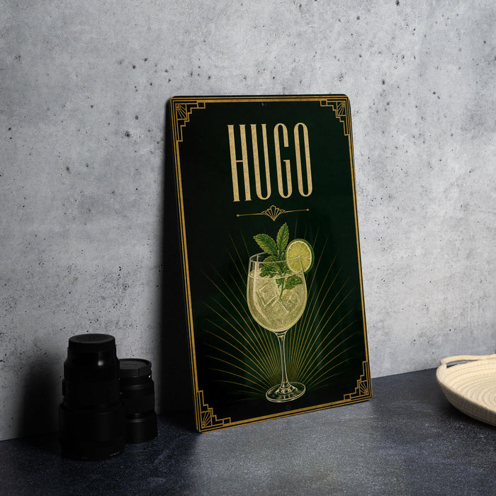 A poster or sign with the word "HUGO" prominently displayed, featuring an illustration of a cocktail glass with a lemon slice and a mint leaf.