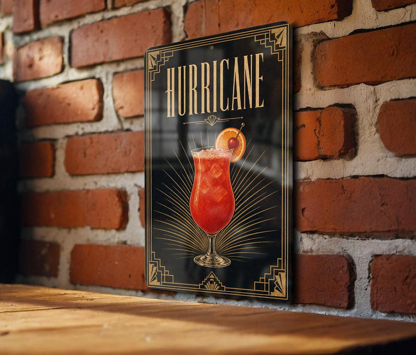 A framed poster of a cocktail with the word "HURRICANE" written on it, displayed on a brick wall.