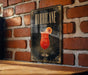 A framed poster of a cocktail with the word "HURRICANE" written on it, displayed on a brick wall.