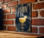 A poster with a glass of jasmine cocktail and a flower on a brick wall.