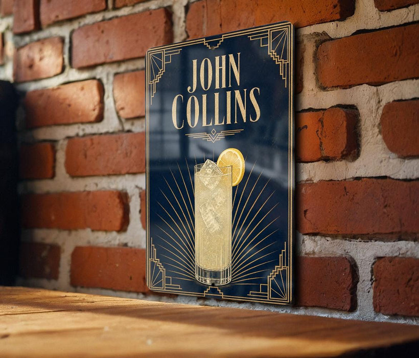 A sign for John Collins cocktail is displayed on a brick wall, featuring an illustration of a cocktail glass with a lemon slice.