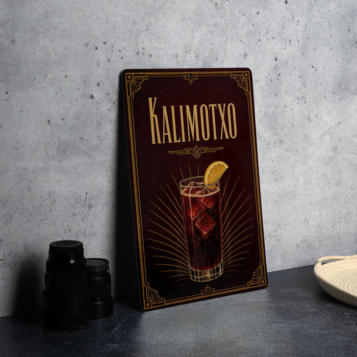 A framed illustration of a cocktail with a lemon slice, accompanied by the text "KALIMOTXO" on a dark background.