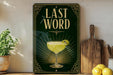 a decorative sign with the text "LAST WORD" and an illustration of a cocktail glass with a lime on a wooden surface.