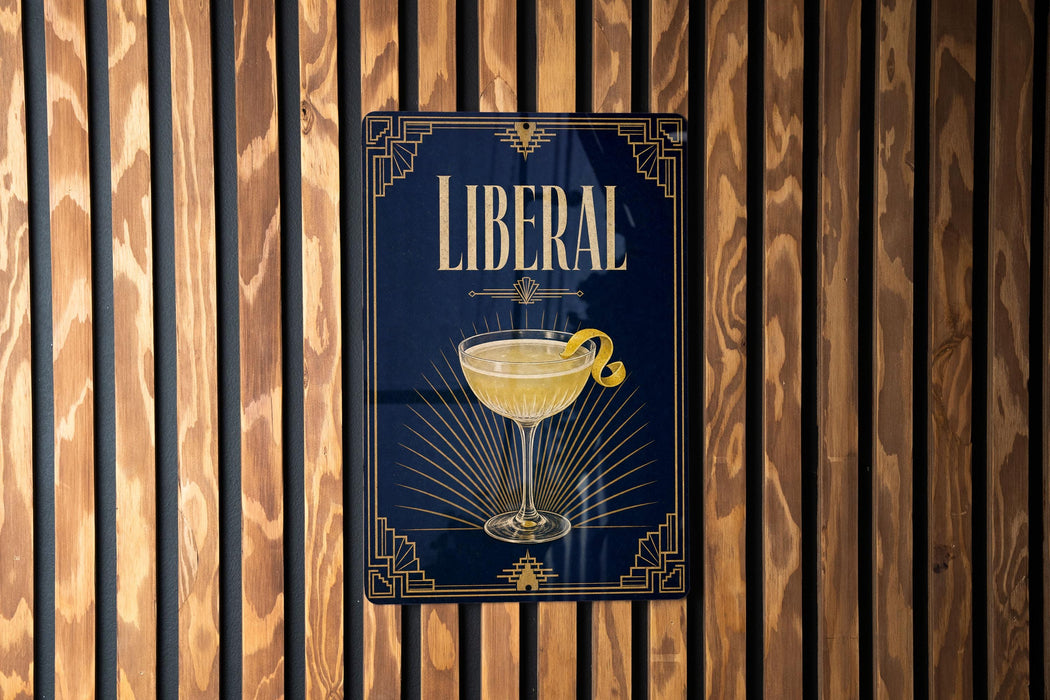 A metal sign with the word "LIBERAL" on it, featuring an illustration of a cocktail glass with a lemon peel.