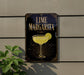 A sign for a lime margarita, featuring a glass of margarita with a lime slice, is displayed on a wall.