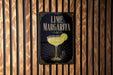A sign for a lime margarita is displayed on a wooden wall.