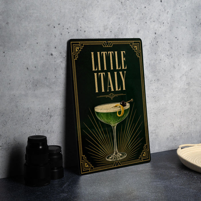 a framed poster with a green background and gold accents, depicting a cocktail glass with a lemon twist.