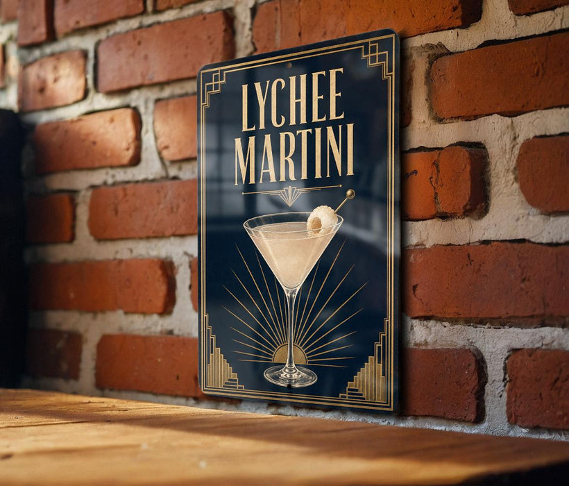 A framed poster of a lychee martini cocktail is displayed on a brick wall.