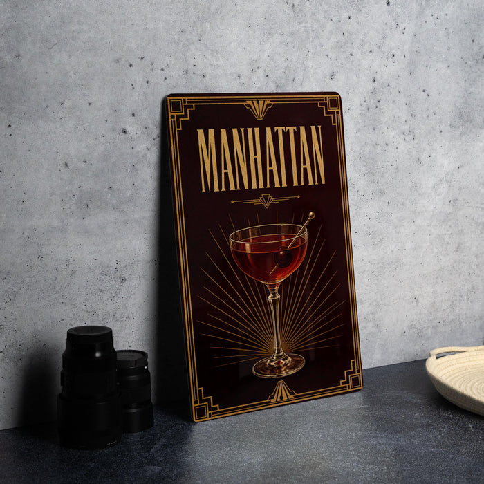 A framed poster of a Manhattan cocktail is displayed on a wall, with a stack of black camera lenses and a white dish visible to the side.