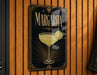 A sign with the word " margarita" written on it, featuring an illustration of a margarita glass with a lime wedge.