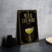 a framed poster with an illustration of a cocktail glass and the text "MEZCAL LAST WORD" on it, placed on a countertop next to some black camera lenses.