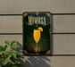 A framed poster of a mimosa cocktail is displayed on a wall, with a plant visible to the left.