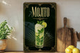 A framed advertisement for a mojito cocktail, featuring a glass of the drink with a lime and mint garnish, is displayed on a wall next to a wooden cutting board and a potted plant.