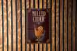 A sign for "Mulled Cider" is displayed on a wooden wall.