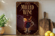 A framed advertisement for "Mulled Wine" featuring a glass of wine with a slice of lemon and a cinnamon stick.