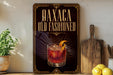 a decorative sign with the text "Oaxaca Old Fashioned" and an illustration of a cocktail glass with an orange peel.