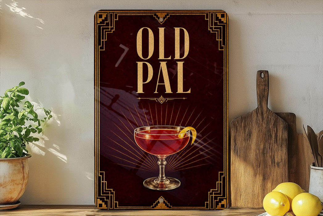 a poster or sign with the text "OLD PAL" and an illustration of a glass of red liquid, possibly a cocktail or wine, with a lemon slice. The poster is displayed on a wall, and there are some kitchen utensils and a potted plant visible in the background.