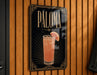 A sign for "Paloma" cocktail hanging on a wooden wall.