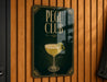 A sign for the "Pegu Club" featuring an illustration of a cocktail glass with a lemon on the side.