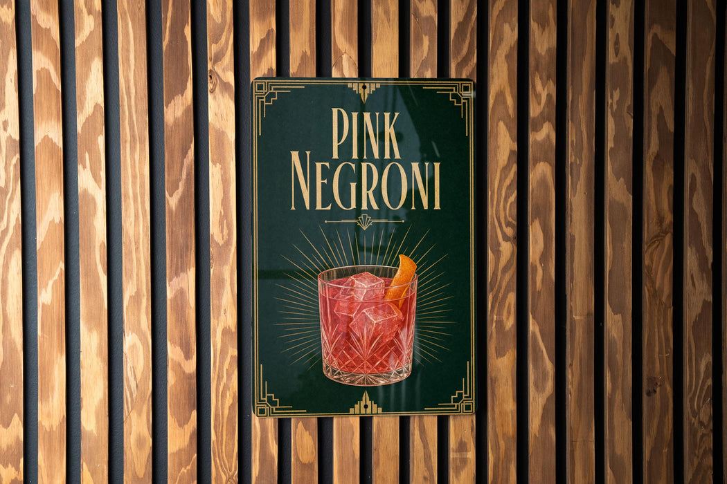A sign for "PINK NEGRONI" cocktail is displayed against a wooden wall.